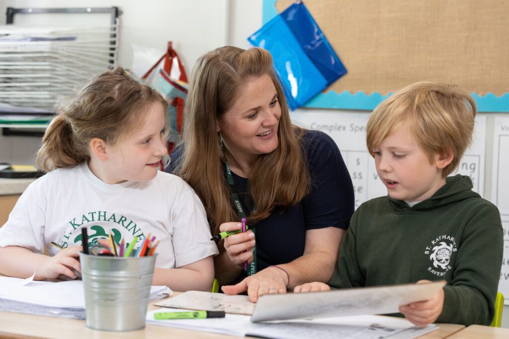 teacher discussing some writing with two children