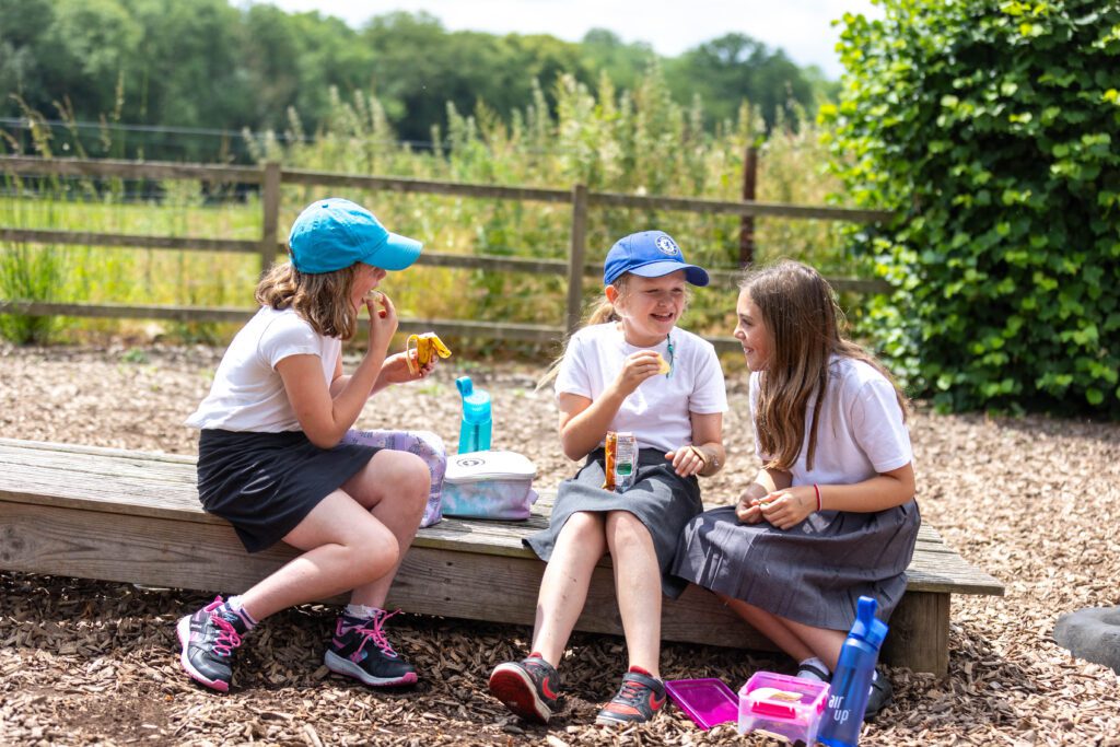 three girls eating packed lunch outside