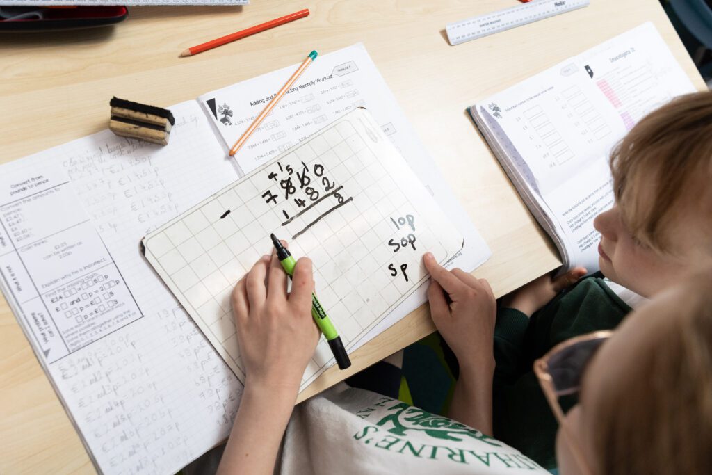 children working out maths on a small whiteboard